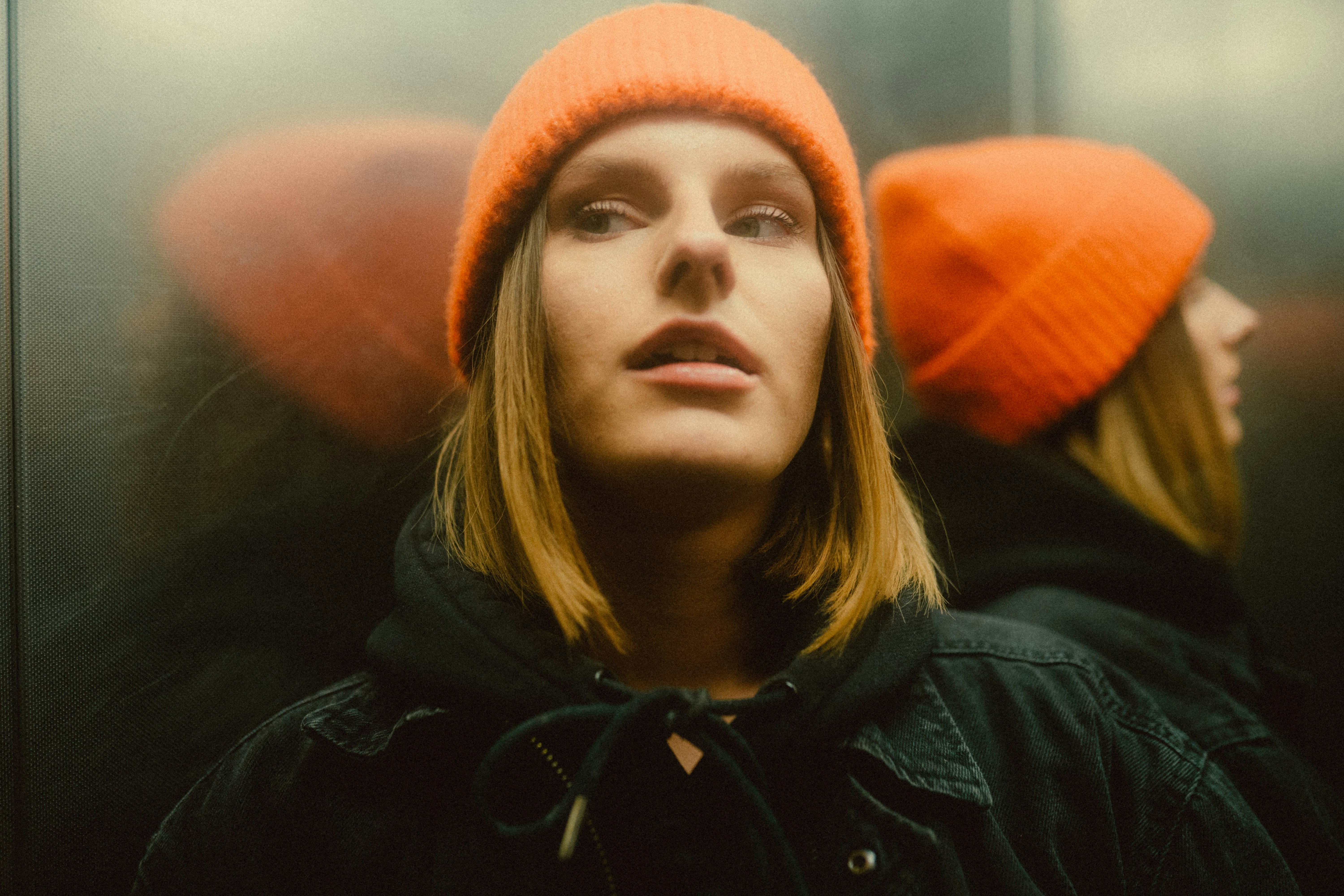 woman in black jacket and orange knit cap